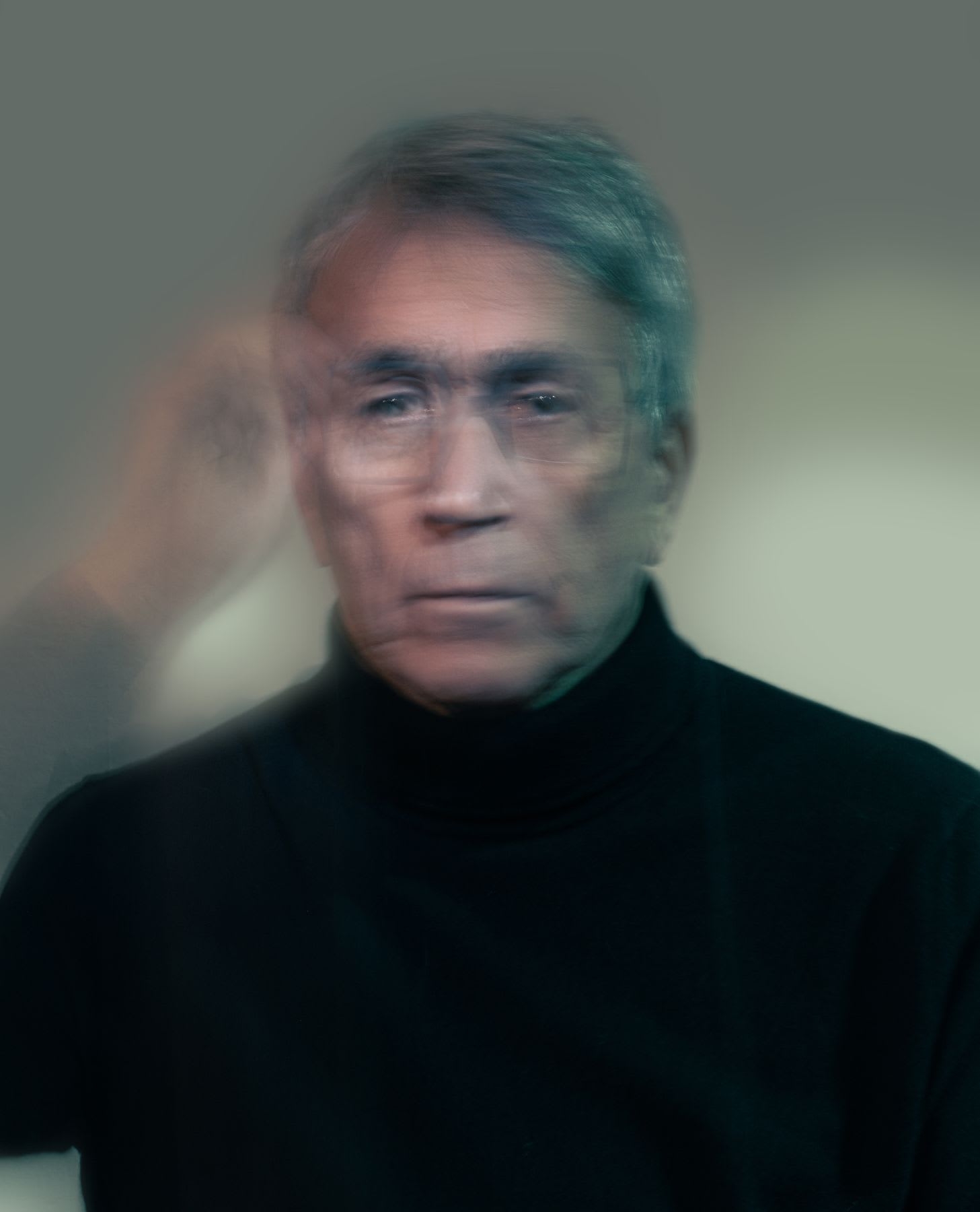 A face of an elderly man wearing glasses is looking forward and he is moving and is blurred