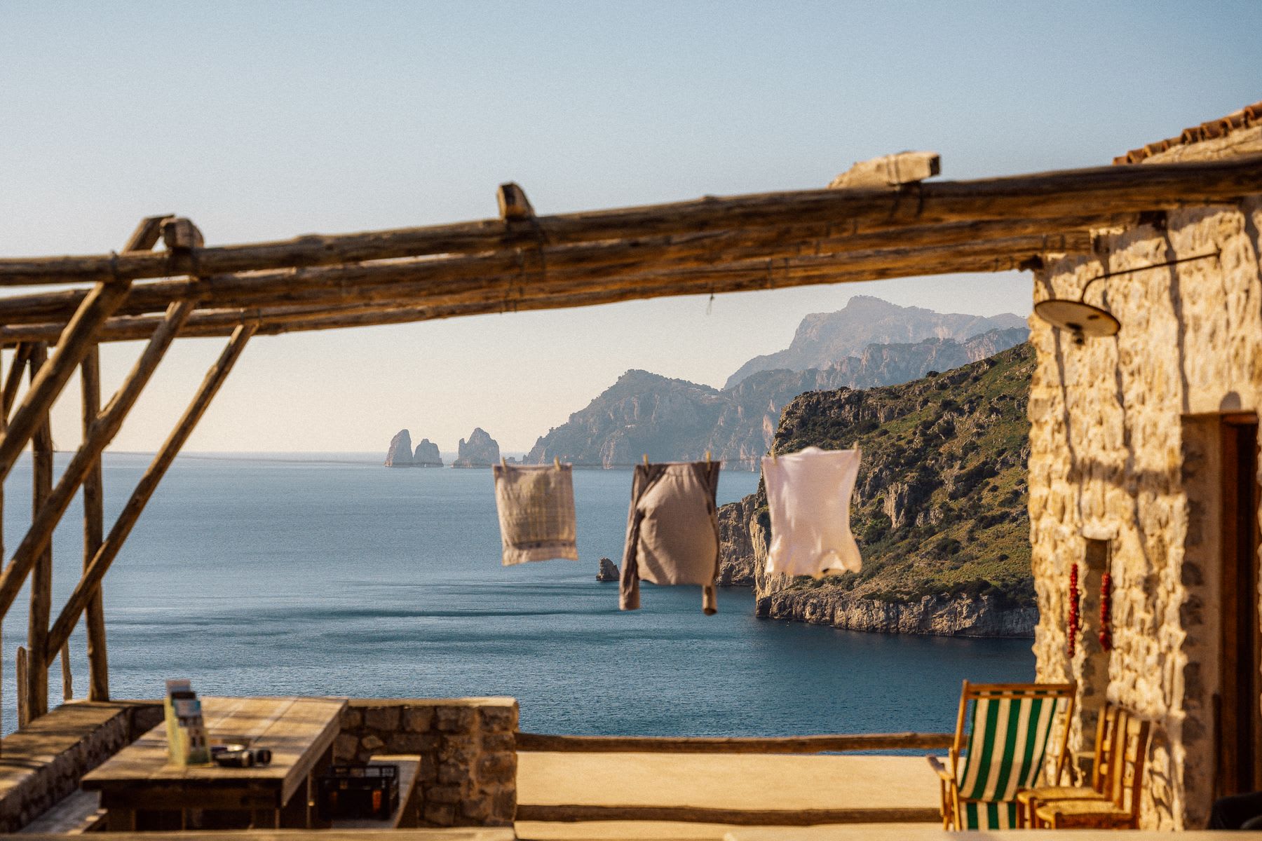 A house on the shore with an ocean view, and clothes hanging on a line during the day.