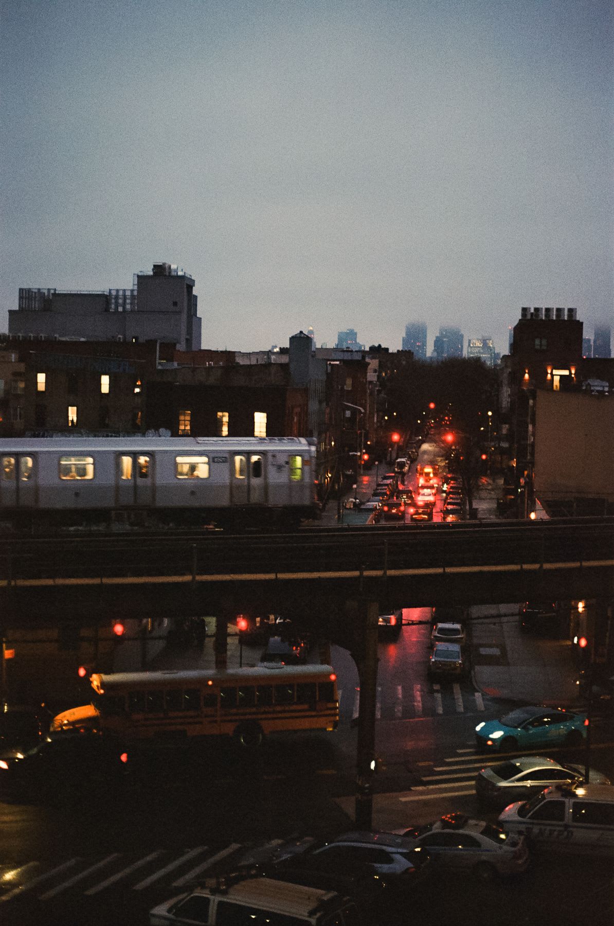 Elevated train passes over a busy city street at night.