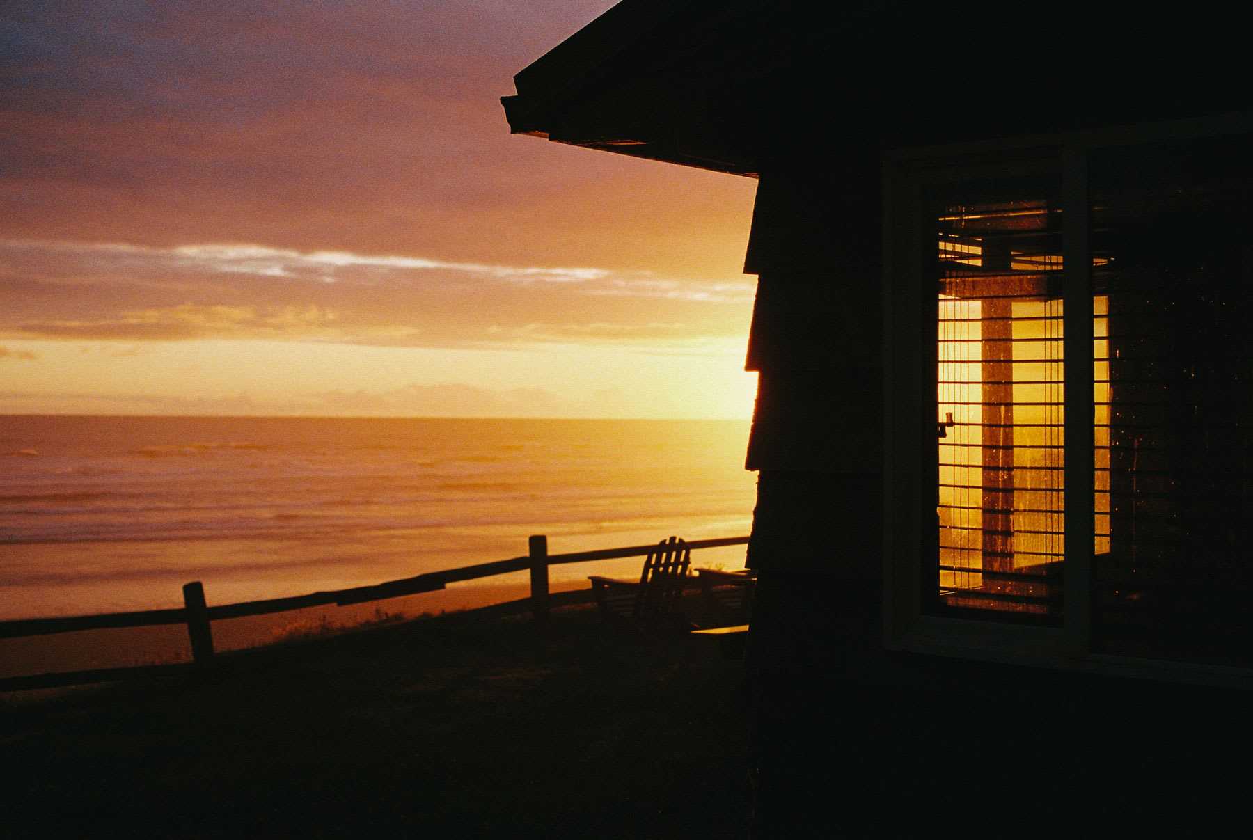 A house that is on the edge of the sea at sunset