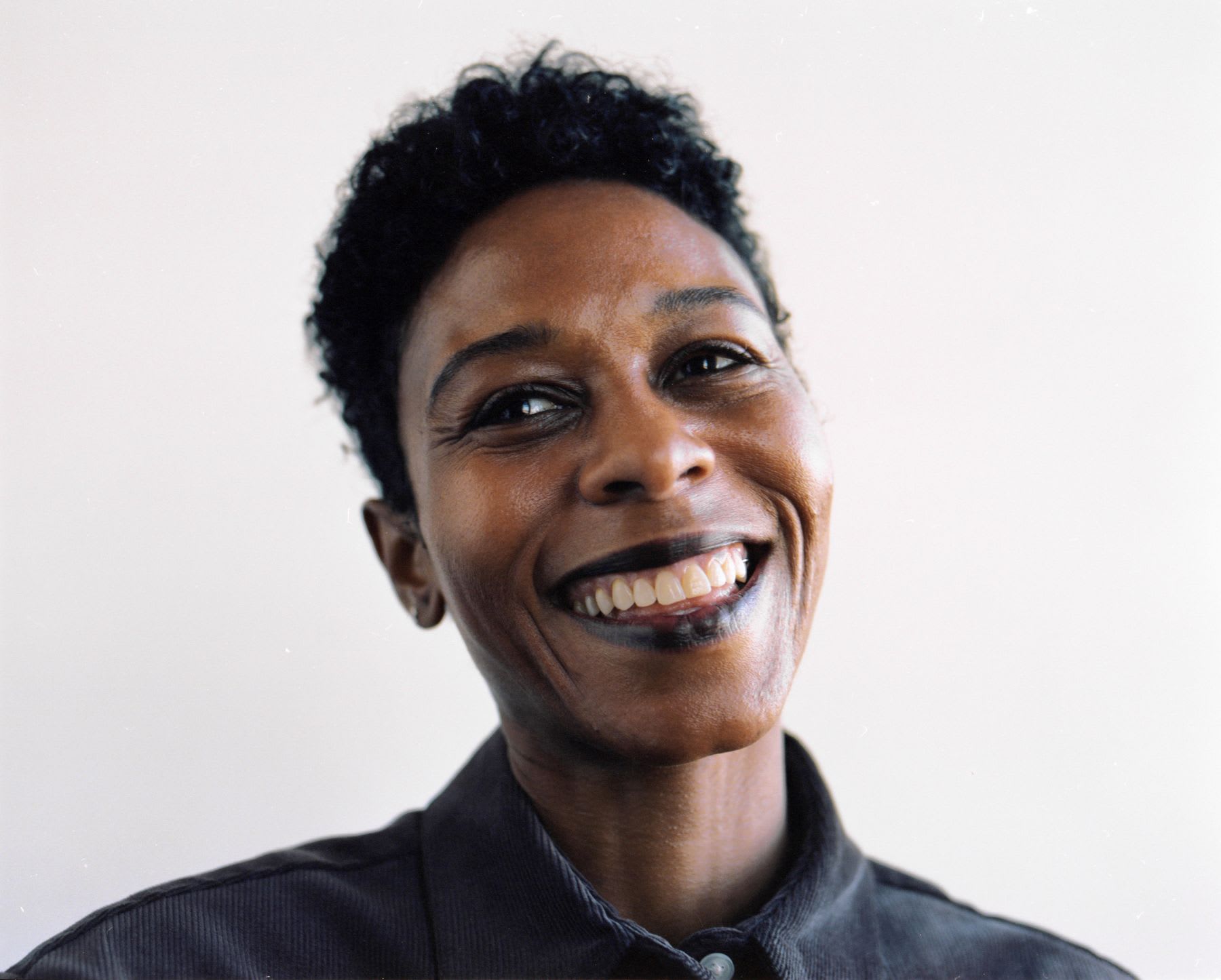 Smiling woman with short hair against a light background.