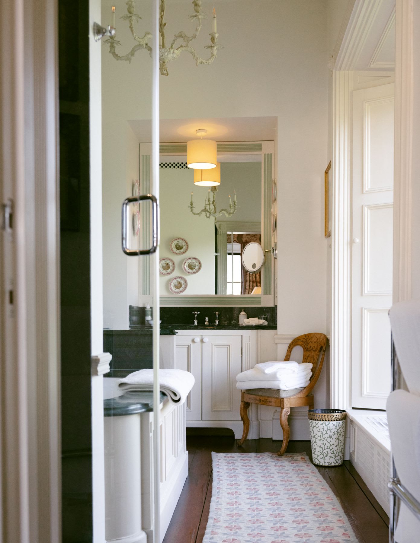 A bathroom has a large mirror above the sink and white cabinetry below it.
