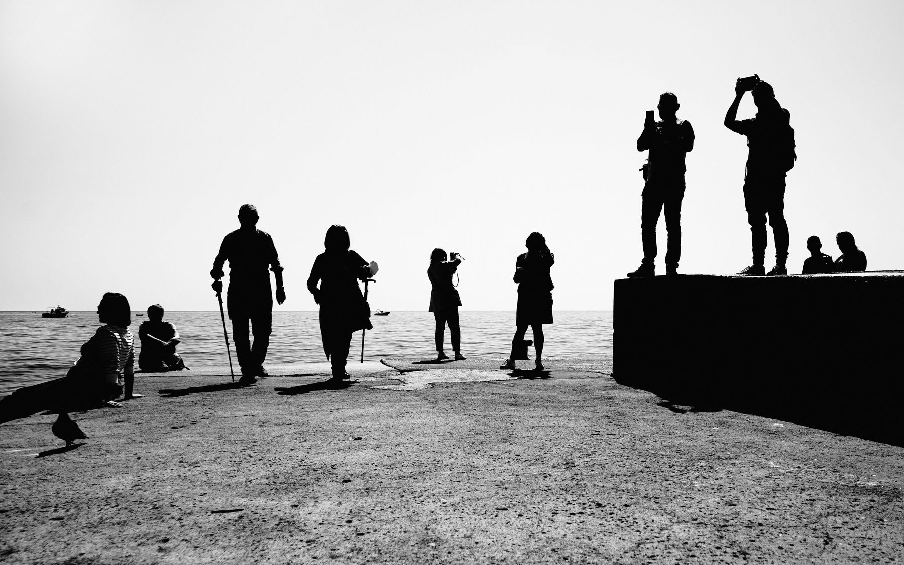 Silhouette of people standing on a platform taking pictures of the ocean