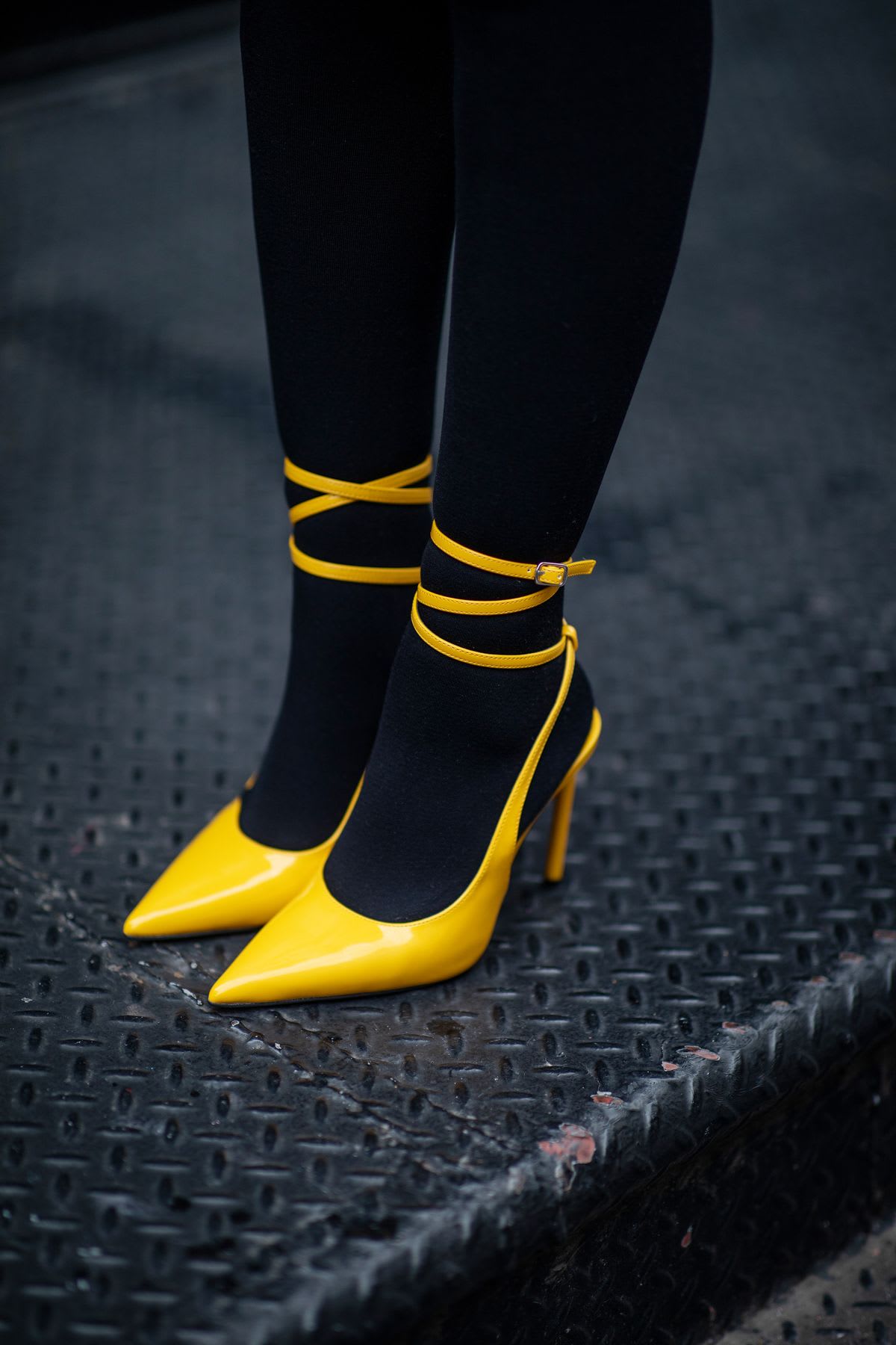 A woman's legs and feet wearing black leggings and yellow high heeled shoes.