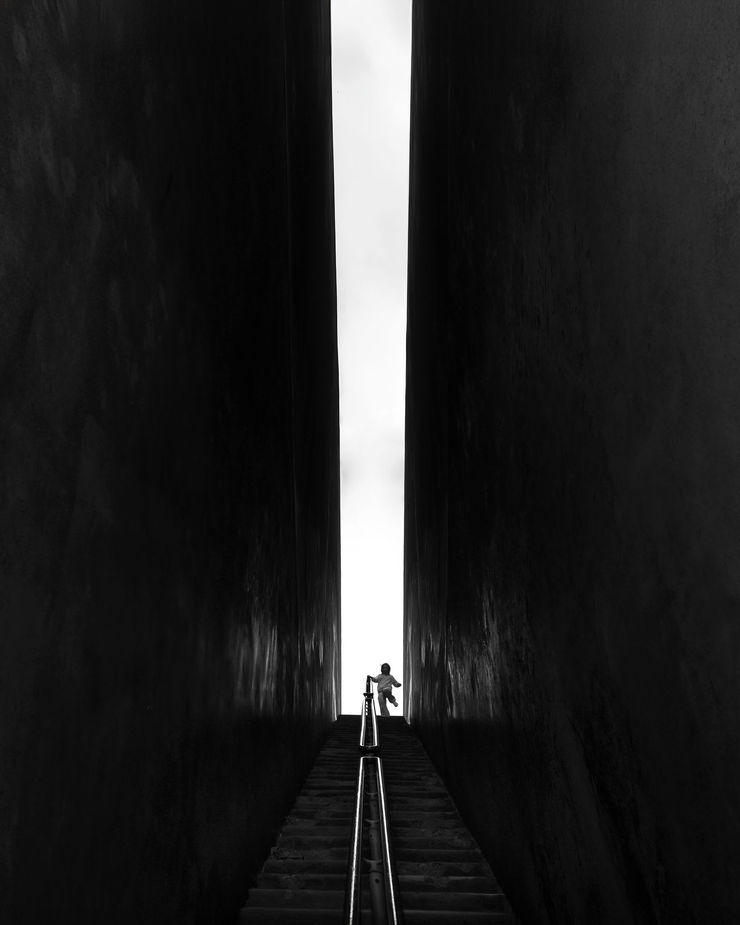 Person is standing between two very high walls at the top of a staircase.