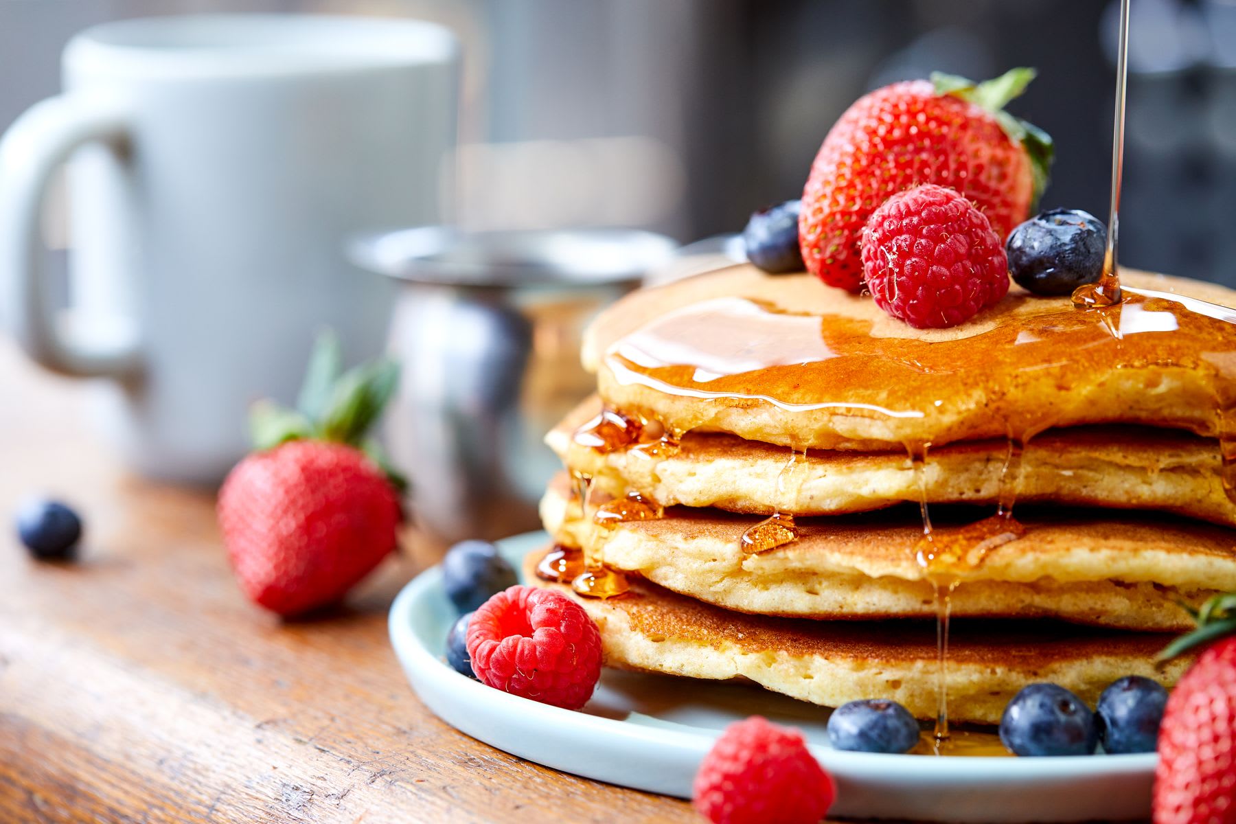 Close-up of a stack of pancakes with fresh berries and maple syrup.