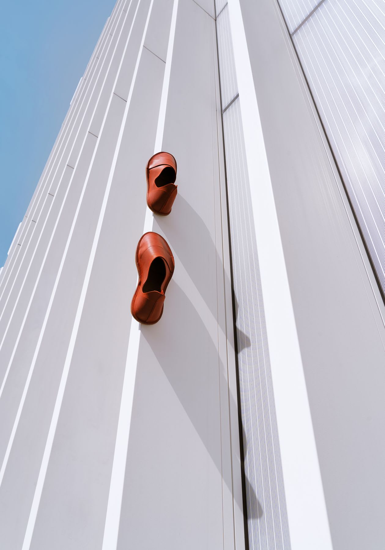 Two orange shoes attached to a tall, white, vertical structure.