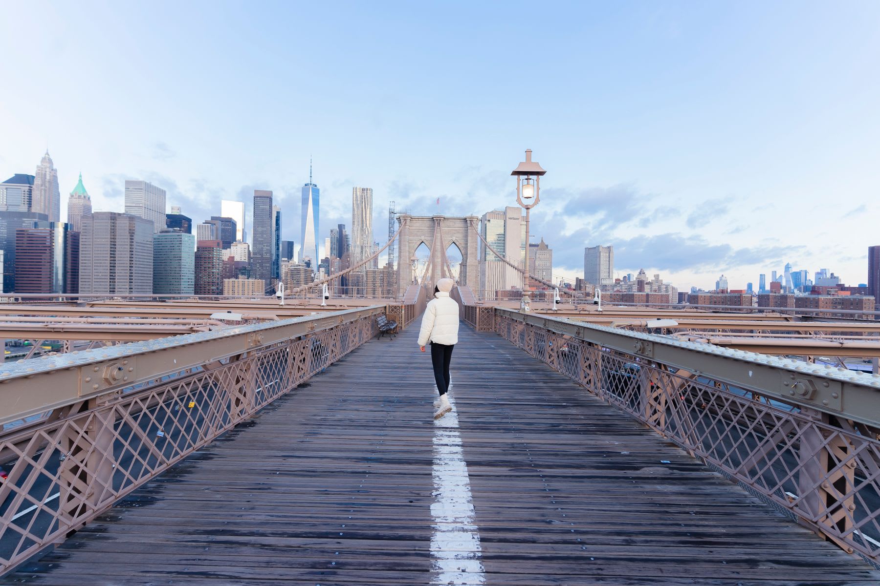 back of a man standing on Brooklyn bridge in the morning