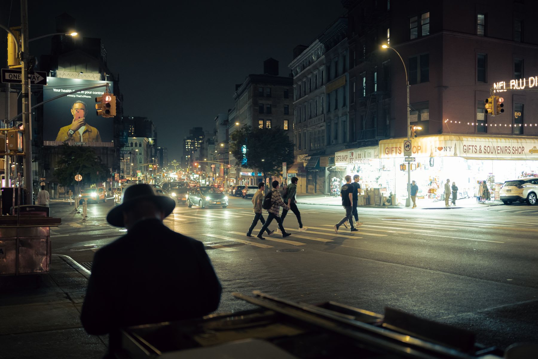 Urban city street with vehicle traffic and pedestrians walking at night