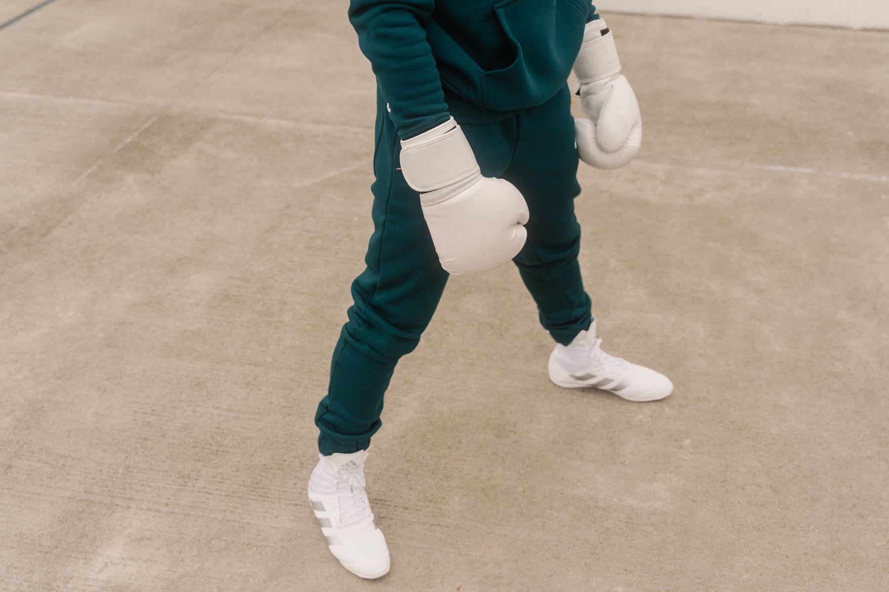 Person with white boxing gloves in an environment with a gray concrete surface.