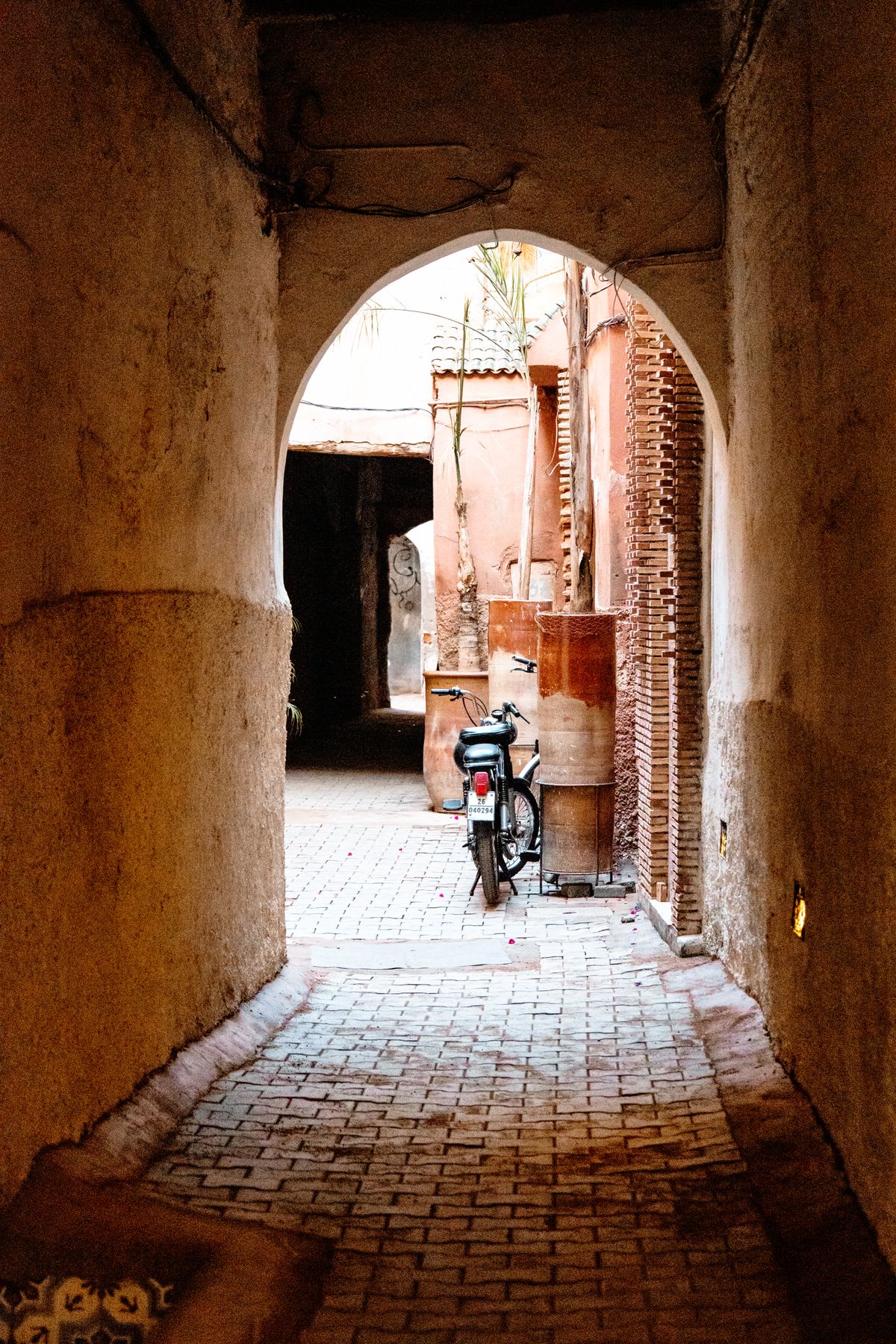 Moped parked outside of a building arch in an alley