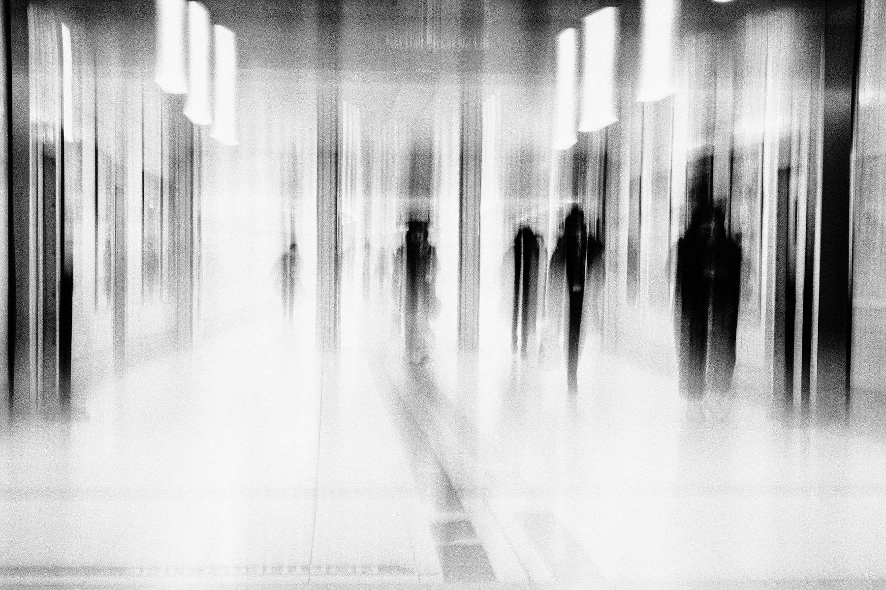 a group of people walking in a hallway, creating a sense of movement and anonymity.