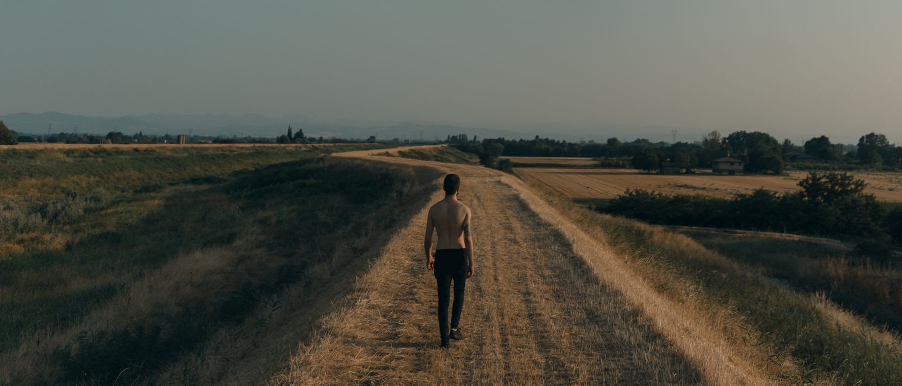 A man walks down a dirt road.