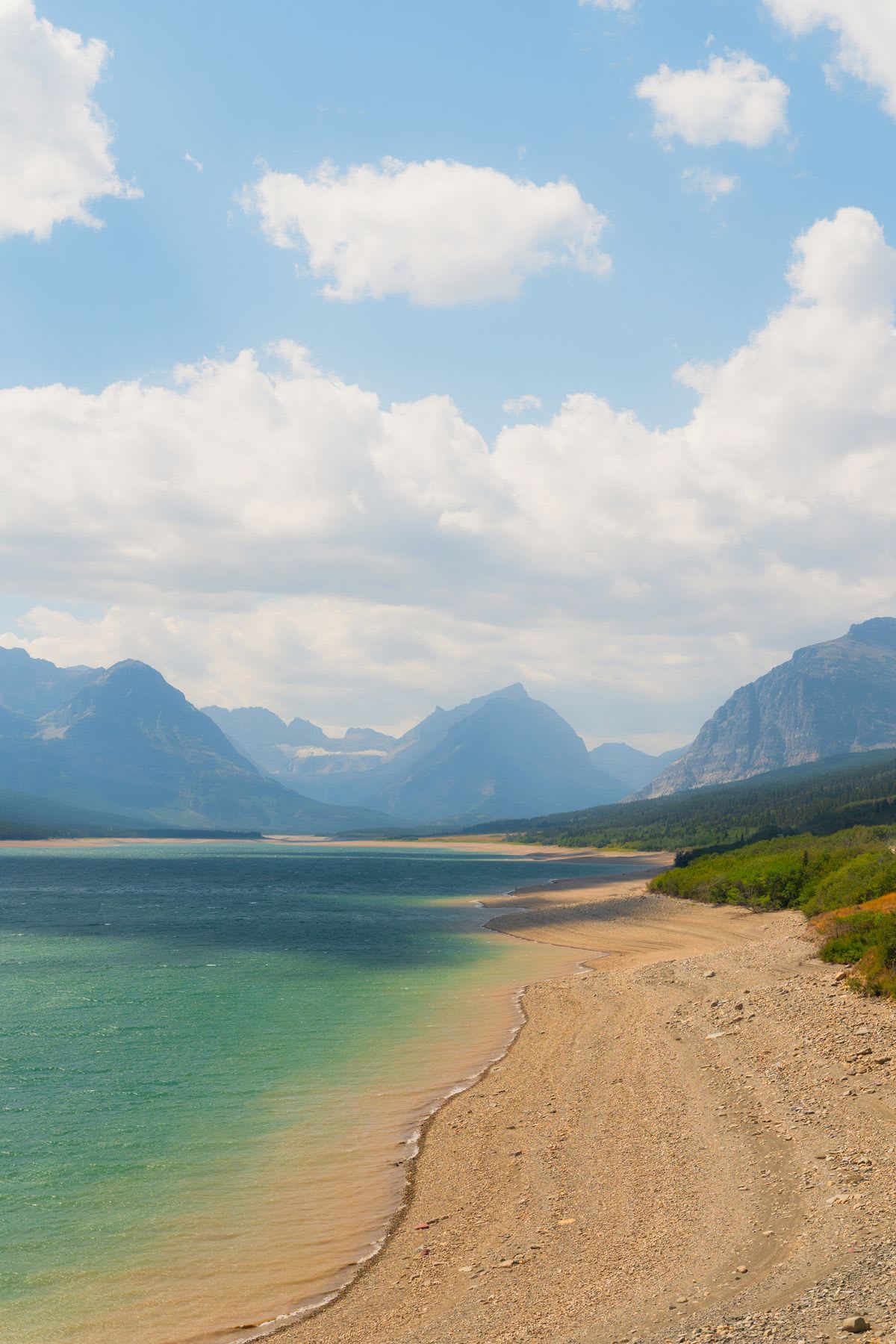 A highland on the beachside is surrounded by mountains in the surrounding environment.