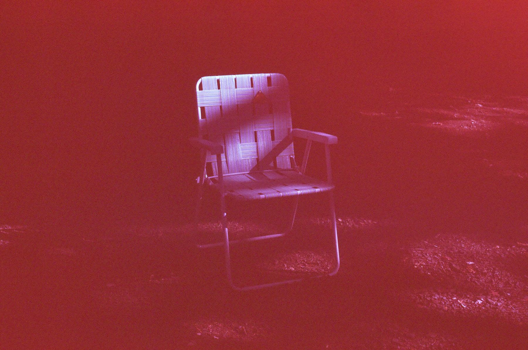 A colorful lawn chair sits alone in a vast field