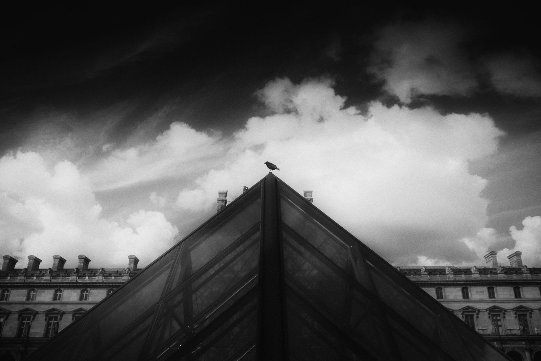 A tall building stands against a cloudy sky in a captivating black and white composition