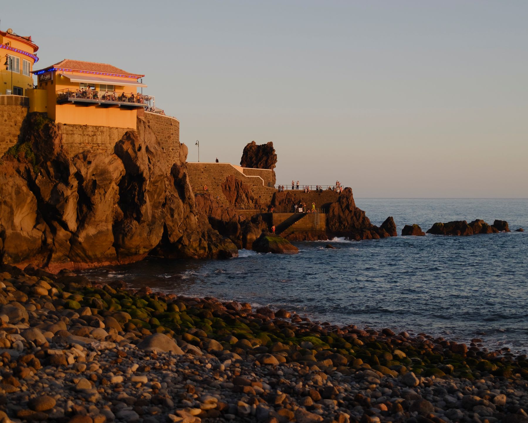 A panoramic view of a coastal landscape with a building on top of a rock formation