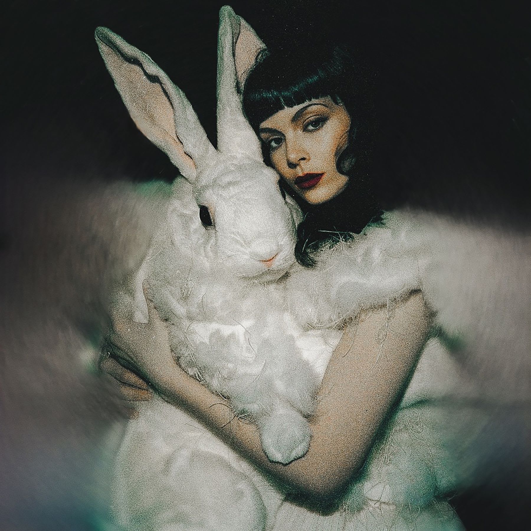 a woman covered in fur is holding a giant white rabbit
