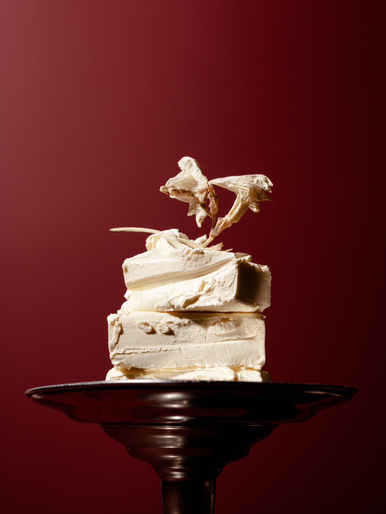 A white cake on a black object and a red background