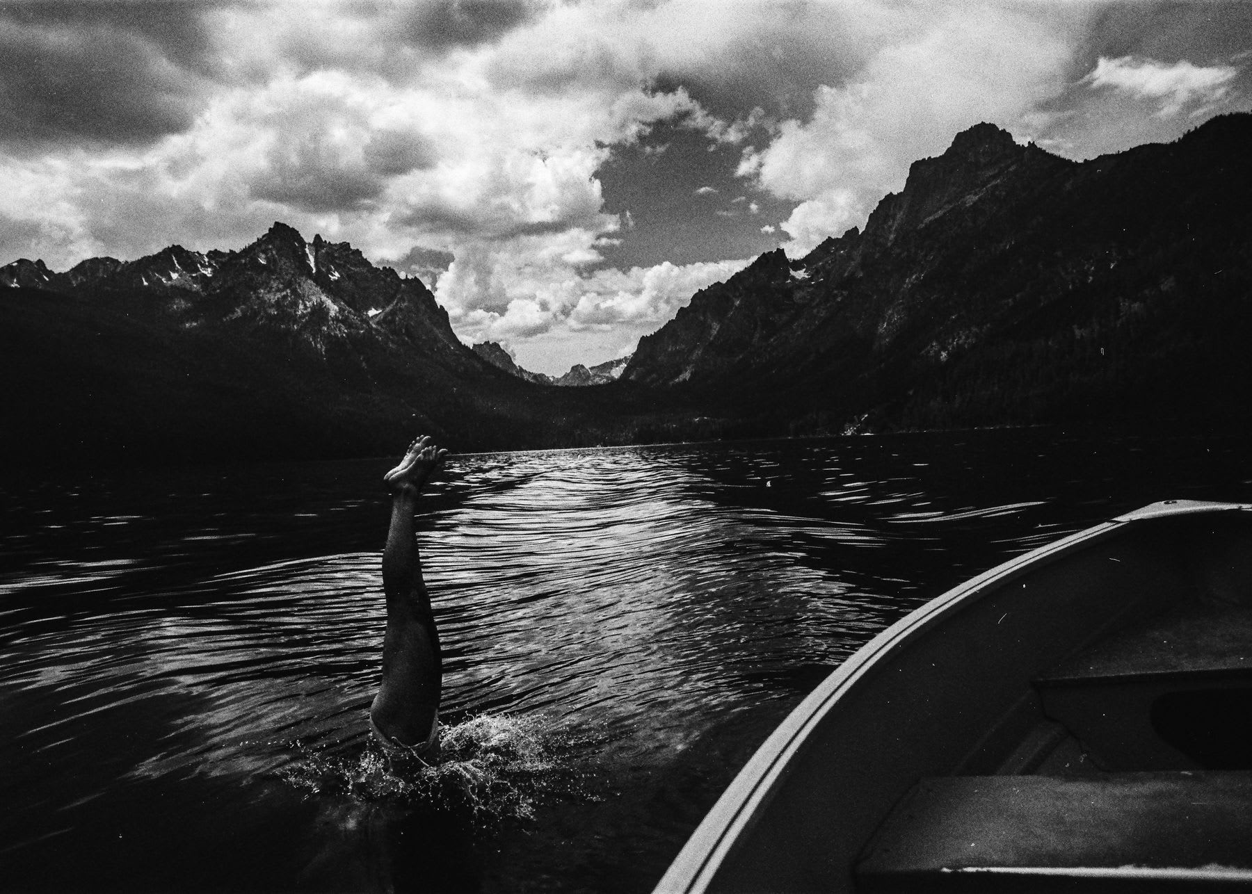 A person diving off a small boat into a lake.