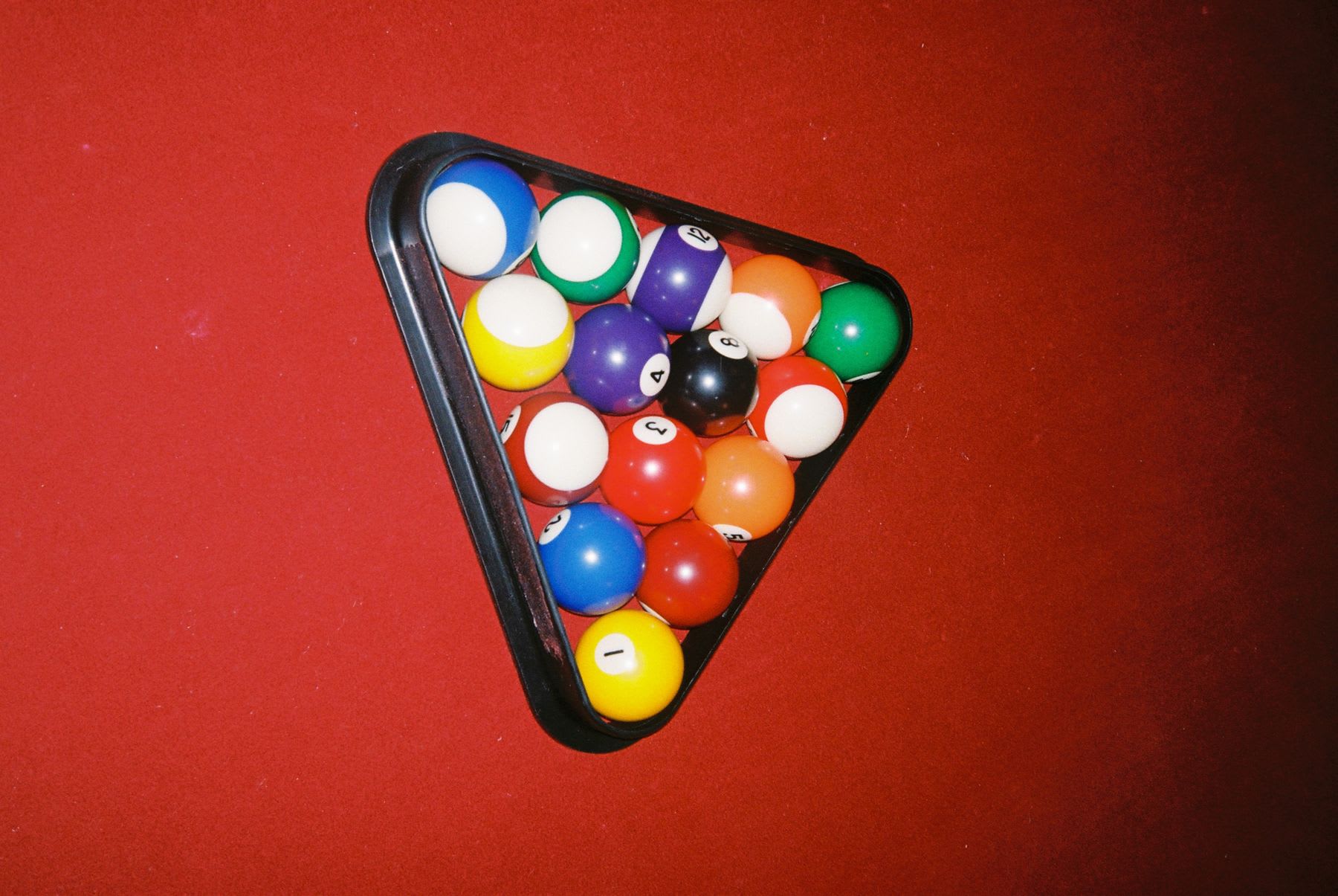 Billiard balls arranged in a triangle on a red background.