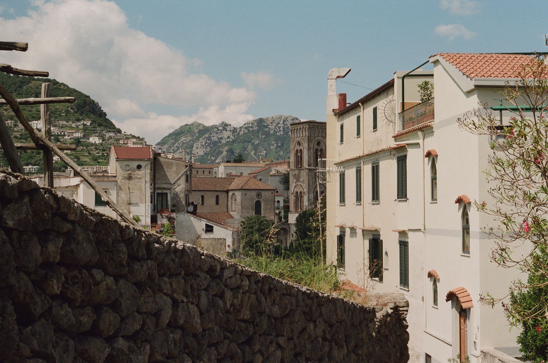 A picturesque scene of an old town built in the mountains. Several buildings with traditional architecture are visible, with red roofs contrasting with the white and beige walls.