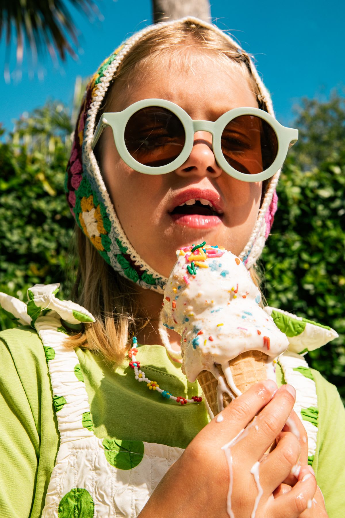 A young white girl holding a melting ice cream cone outdoors