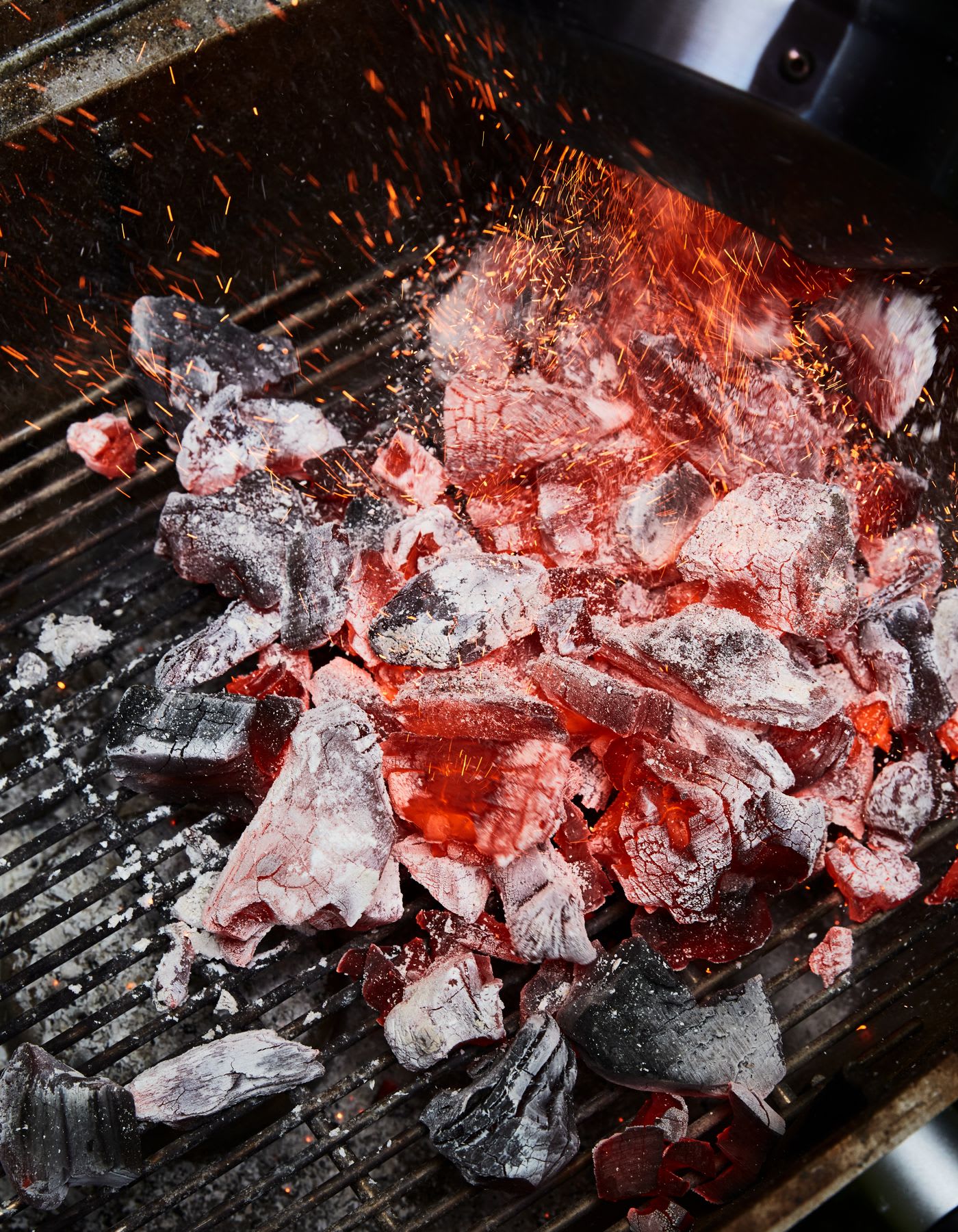 Several pieces of coal that are glowing with several flames and sparks going upwards