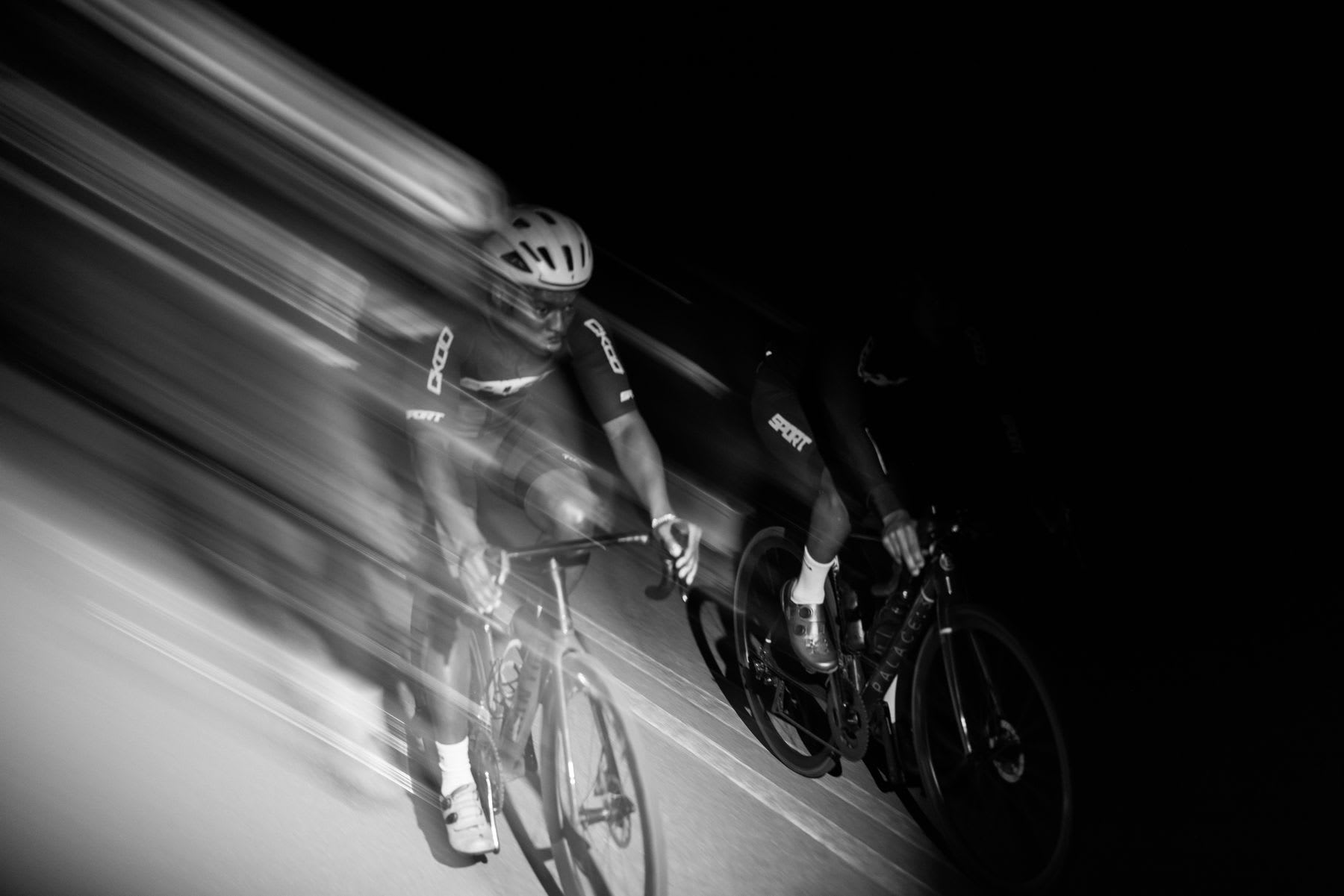 Two people riding bikes on a road at night.