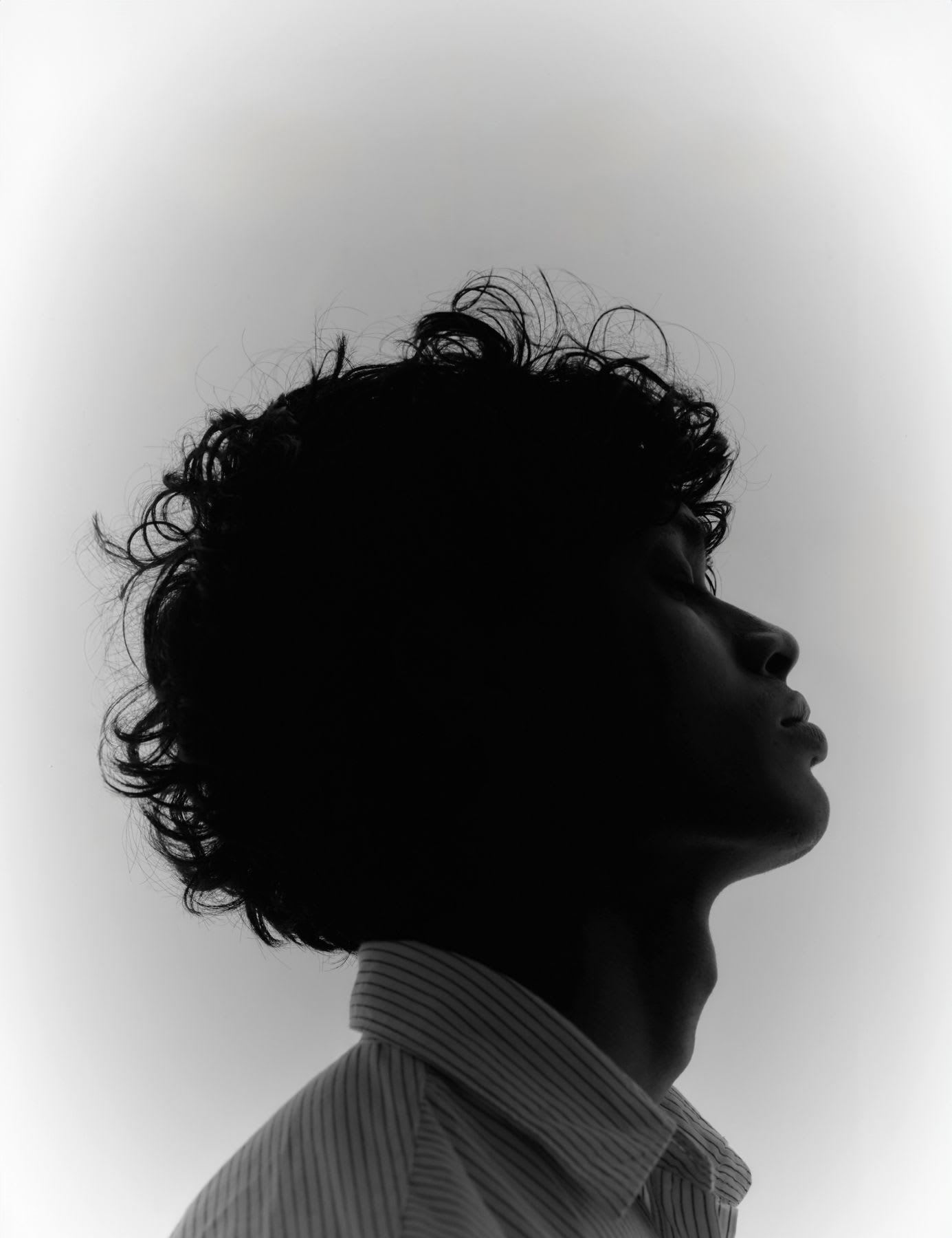 The silhouette of a person in profile on a light, soft background.