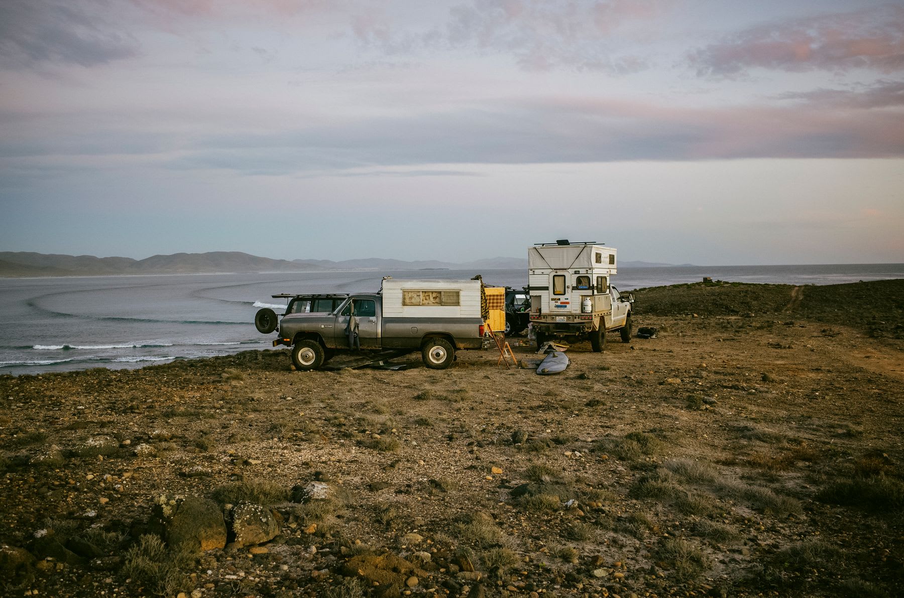 Trucks with camper shells park at the coast on a foggy day.