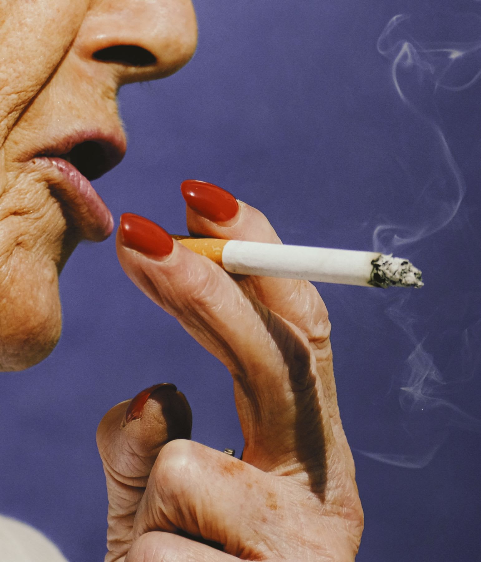 Close up of an elderly womans fingers holding a cigarette