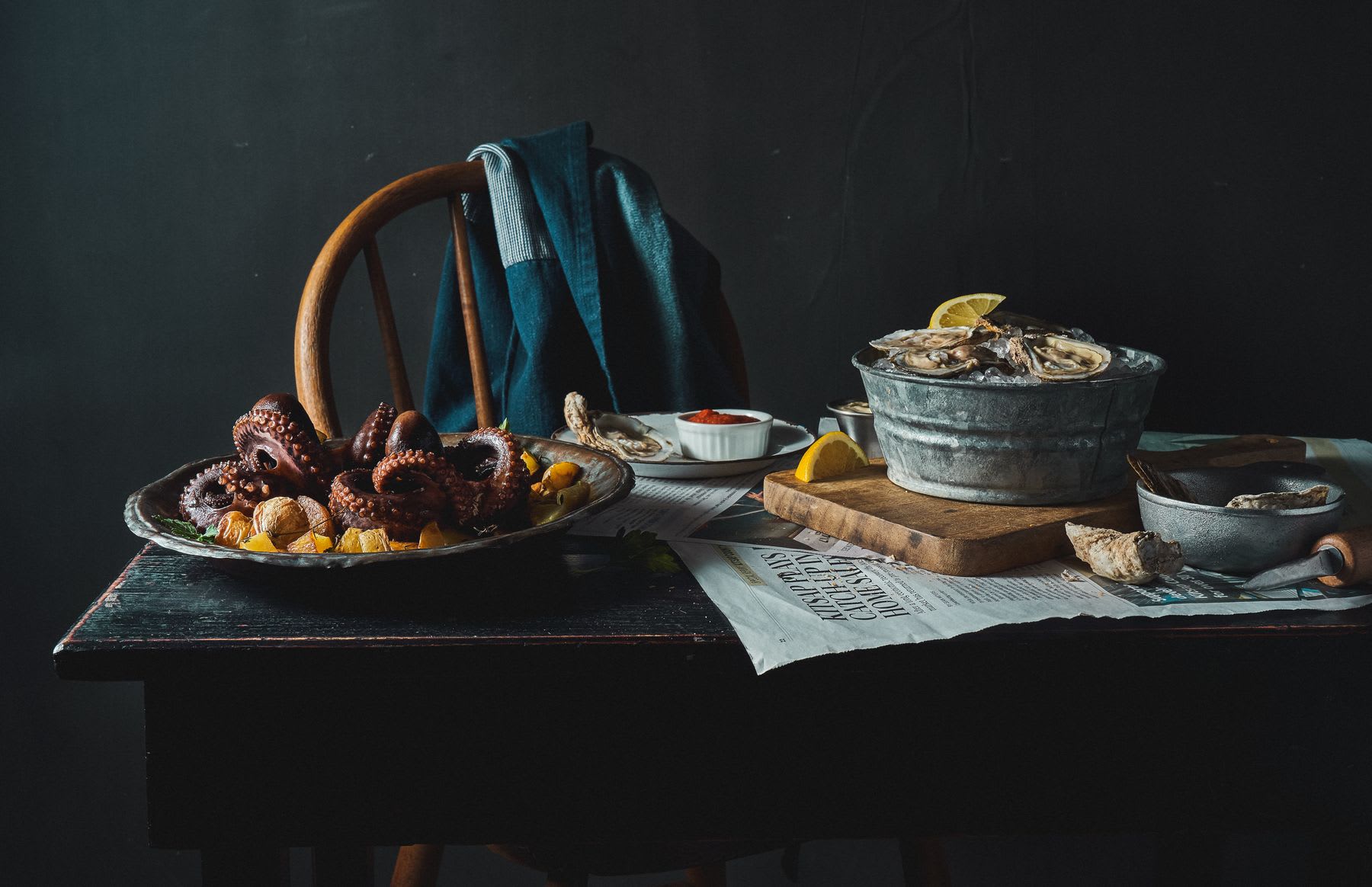 A table with a variety of seafood items and a chair with a jacket behind it