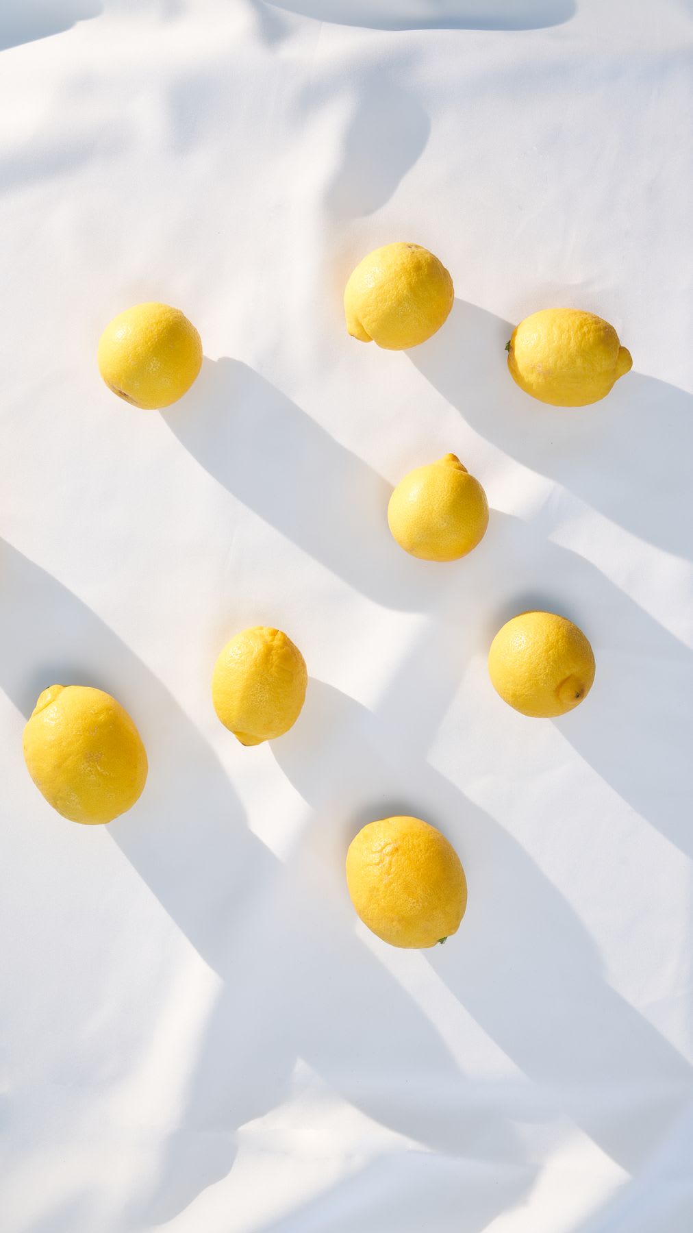 Yellow lemons scattered across a white textured surface.