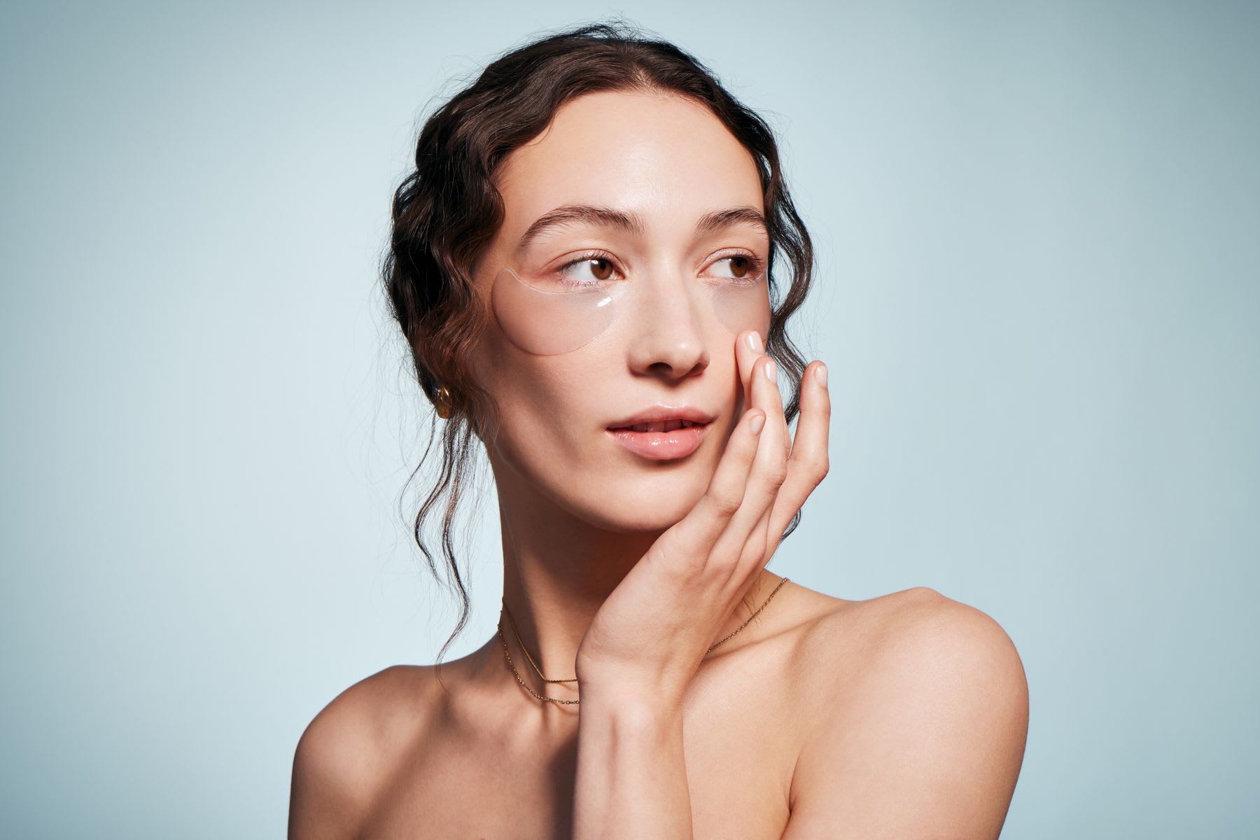 a woman poses to show skincare for under her eyes