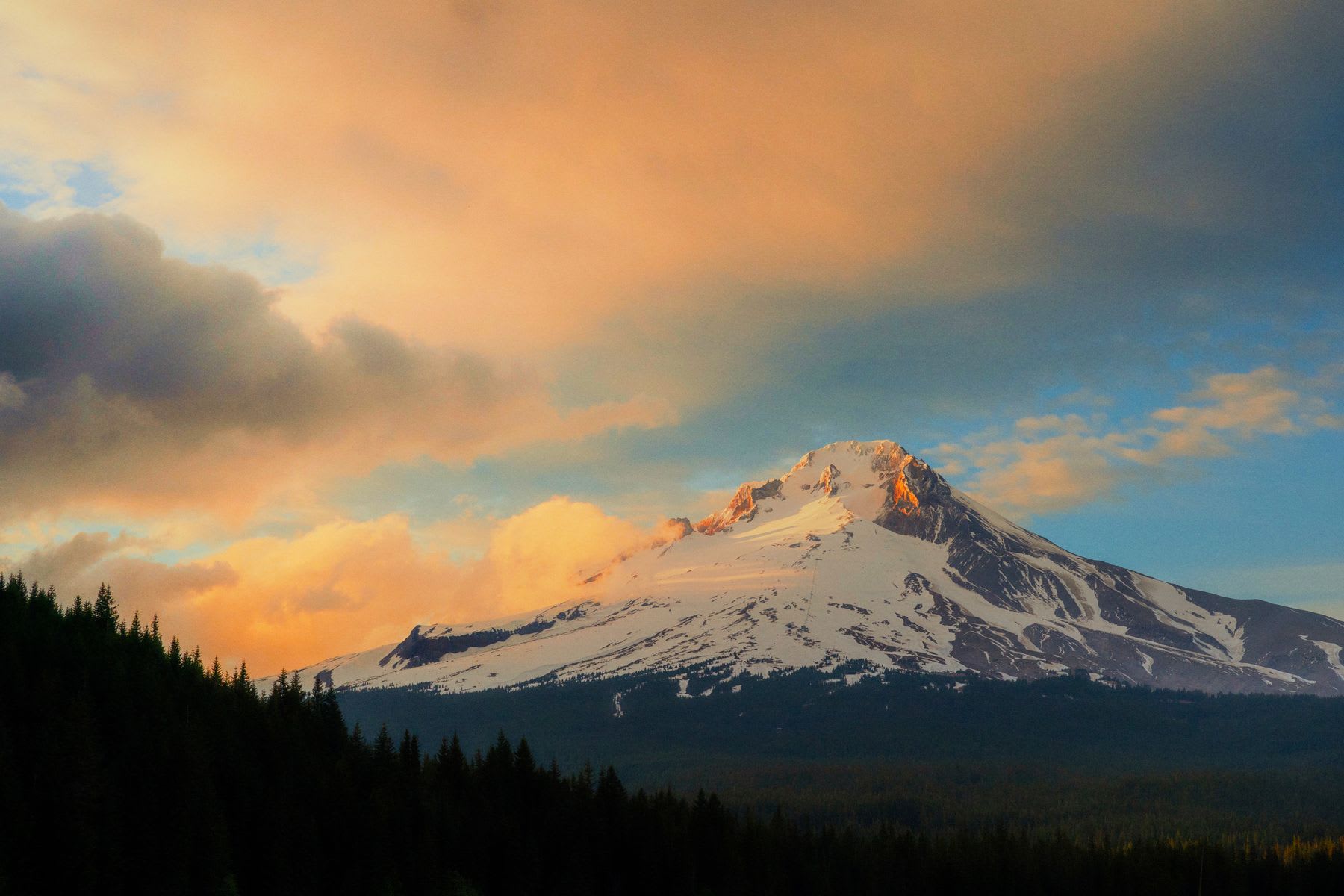 Mount Hood is surrounded by orange clouds at sunset.