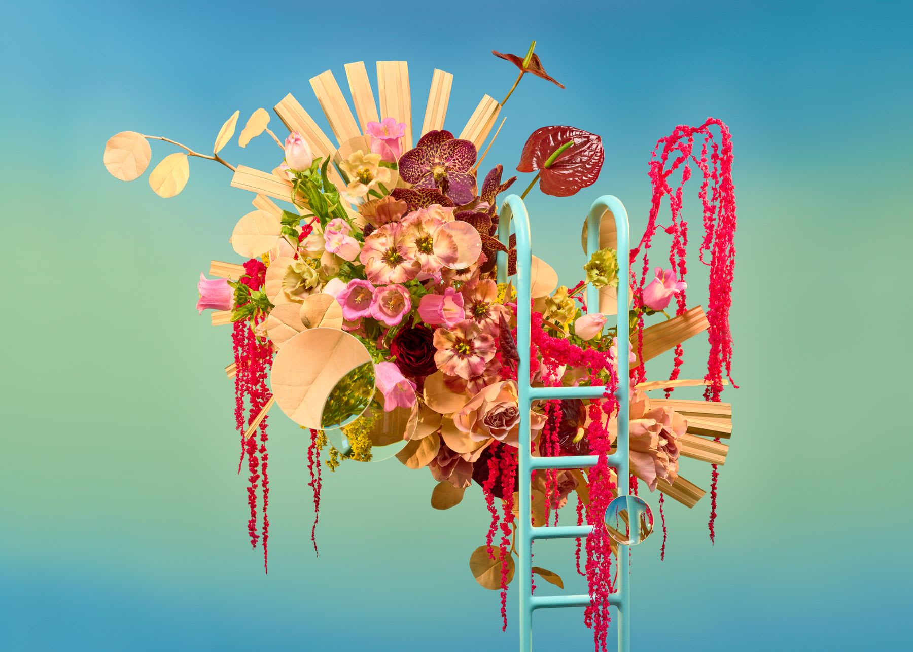 A surrealist art installation features a vibrant bouquet of flowers intertwined with a blue ladder and wooden fan-like structures.