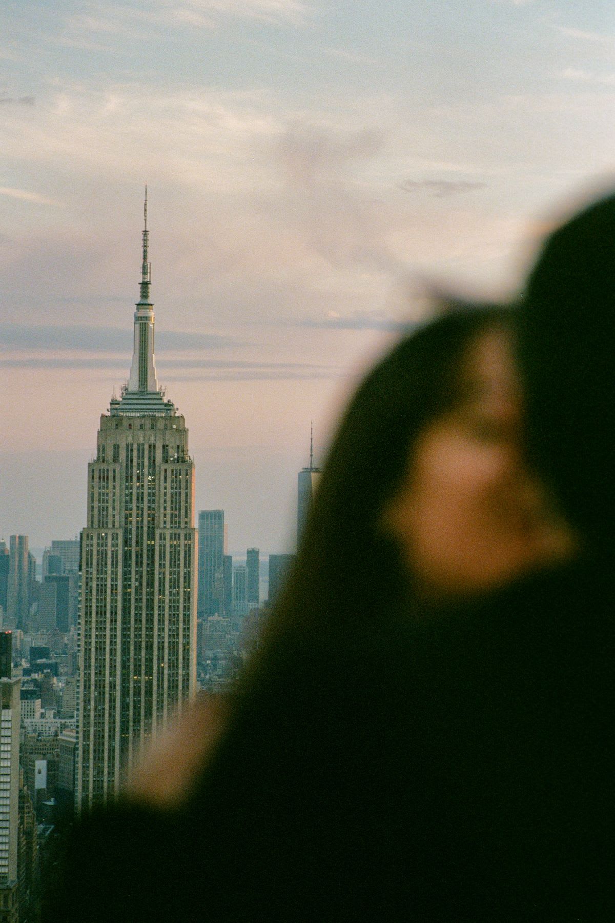 A blurry silhouette of a couple sharing an intimate moment with a view of the Empire State Building and the New York City skyline.