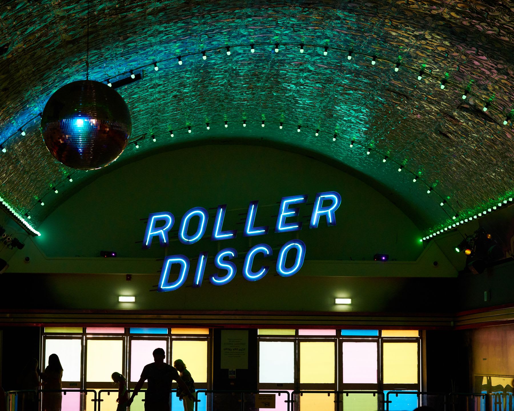 Family visits dimly lit roller disco.