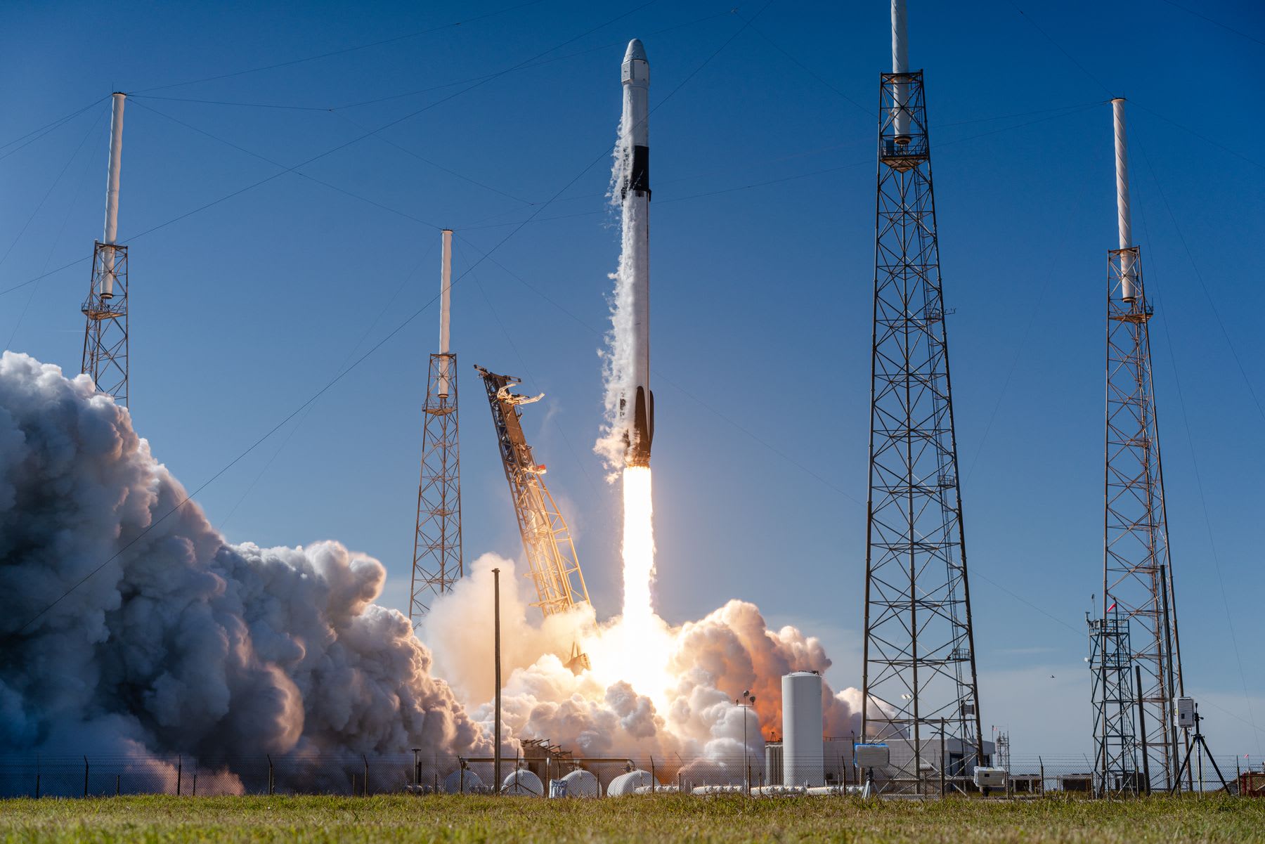 Falcon 9 rocket in early ascent phase with visible exhaust plumes above launch pad.