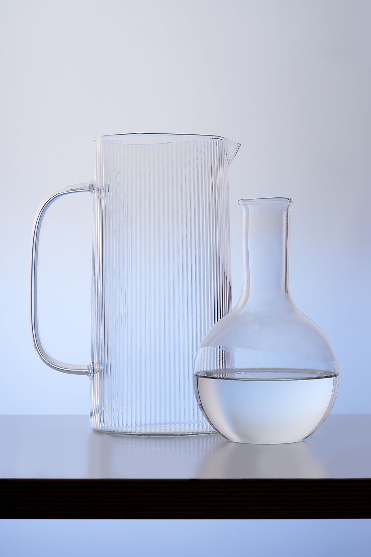 A glass jug is beside a beaker with water in it.
