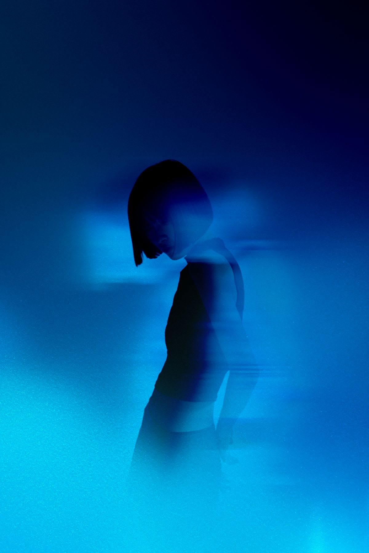 Portrait of a female with cropped black hair against a bright blue background.