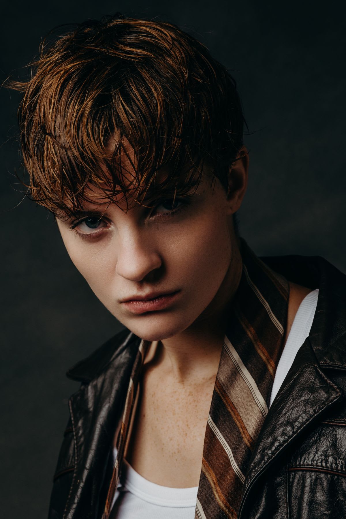 Model wears a jacket with a tie draped around his neck that compliments his hair.