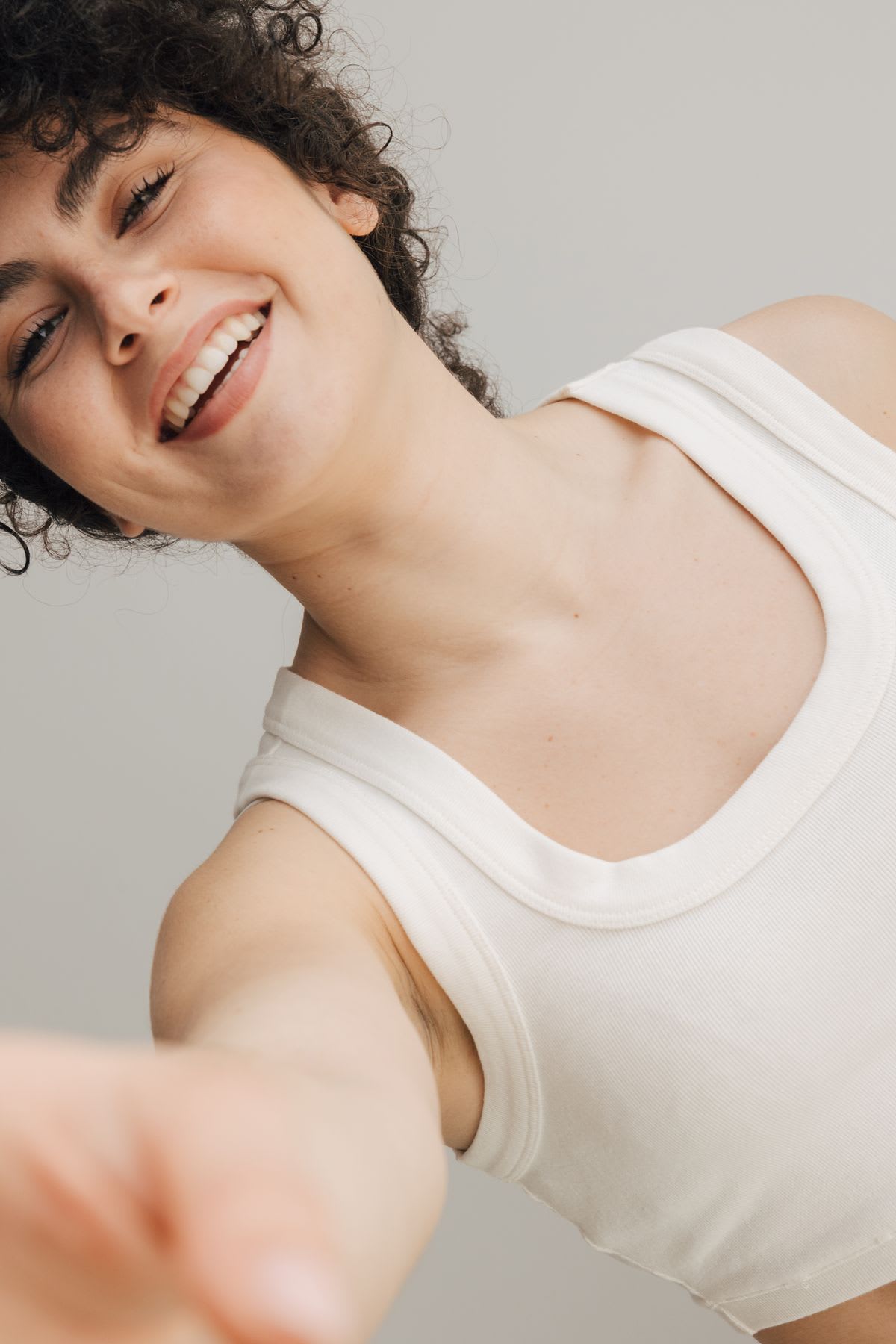 a woman in a white tank top has a big smile as she poses