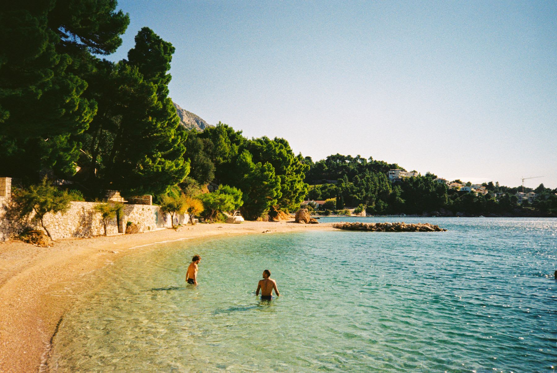 two men are wading in the water at a beach resort