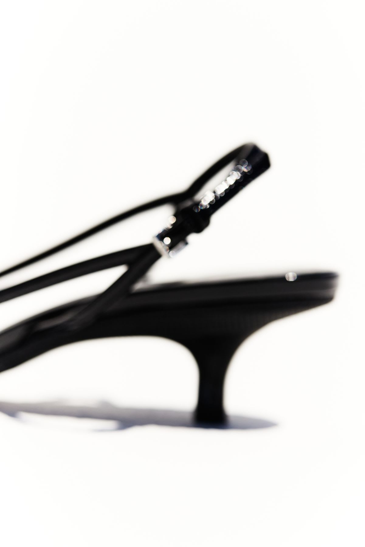 A close up of the back of a strappy high-heeled shoe.