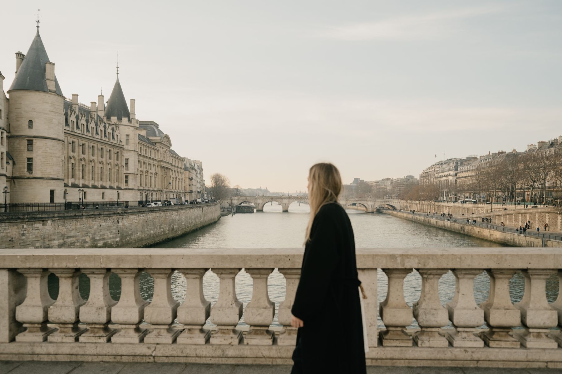 Woman admiring a building with ancient architecture and a canal in the middle of the city