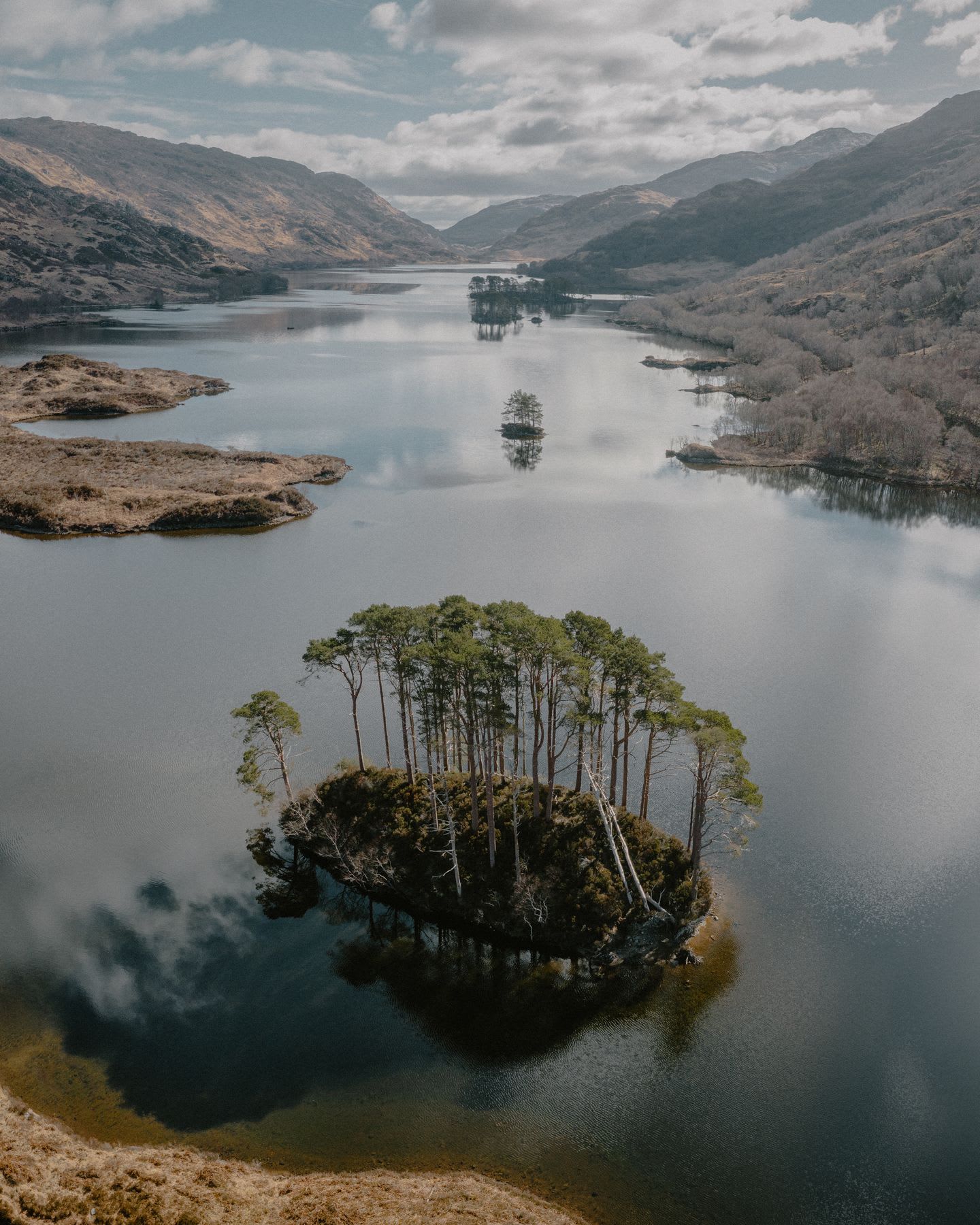 A lake outdoors on a mostly sunny day with small islands in the lake