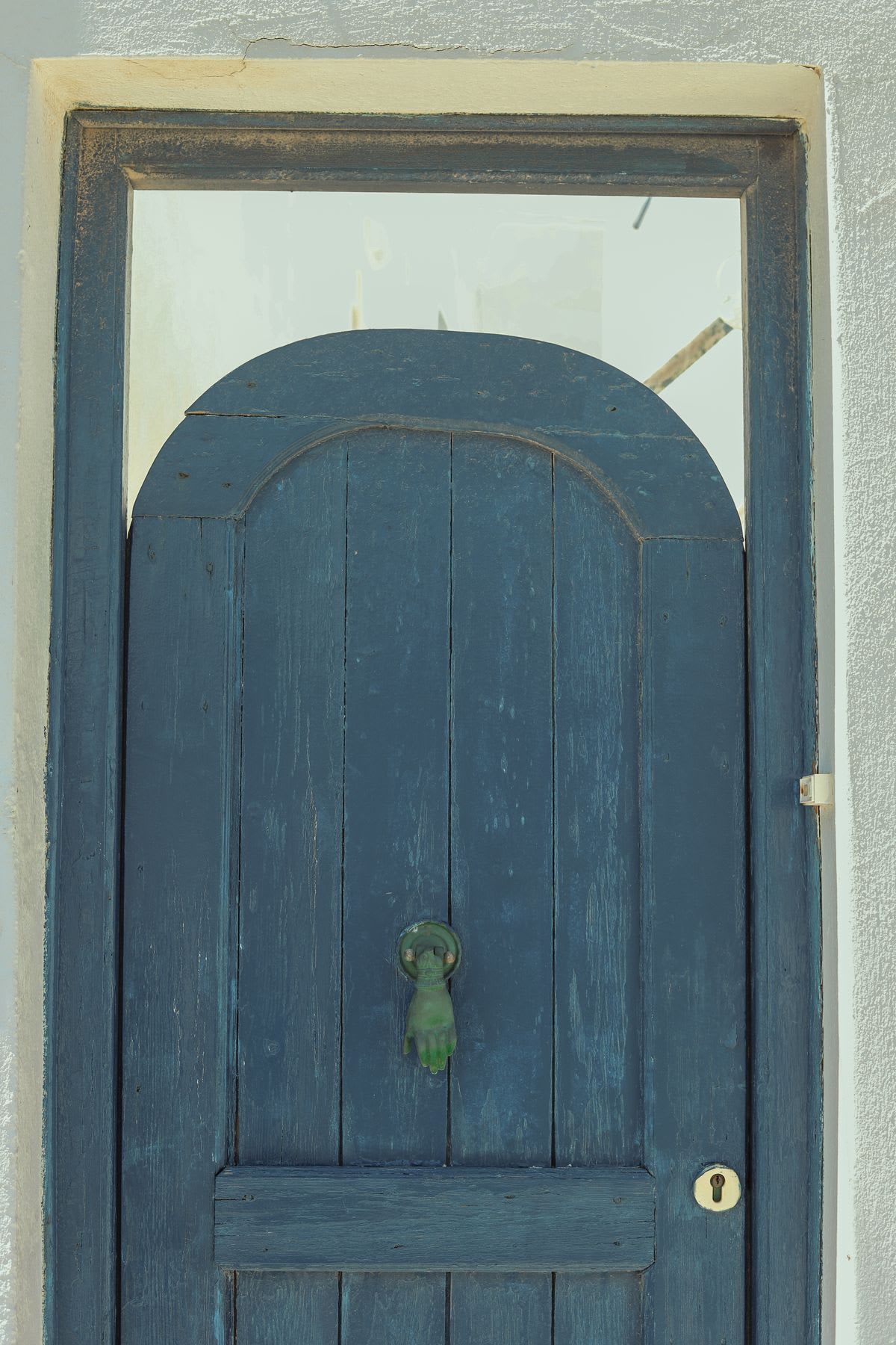 a blue wooden door has been cut into an arch at the top and is in a squared door frame