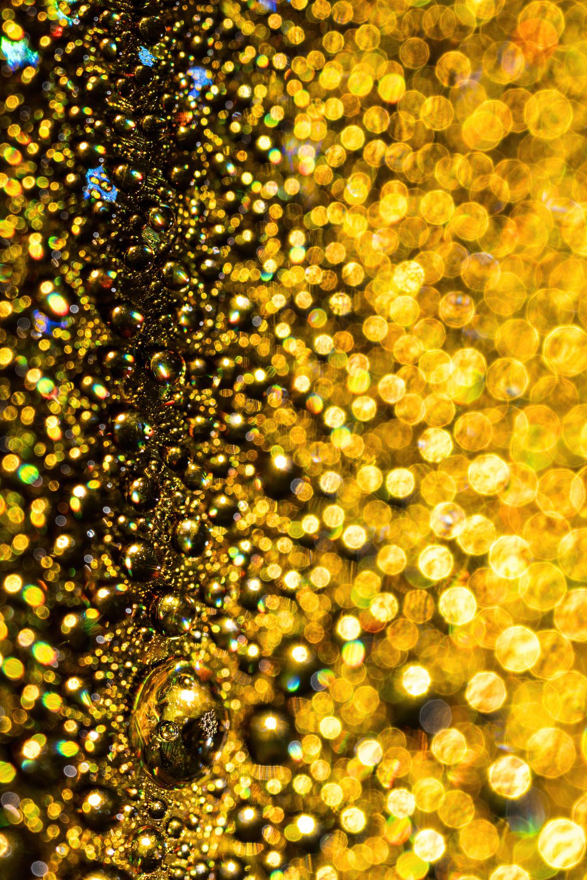 A sparkling close-up of golden water droplets creating an abstract glitter background with bokeh lights.